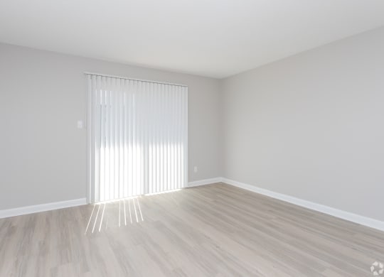 an empty room with white blinds and a window