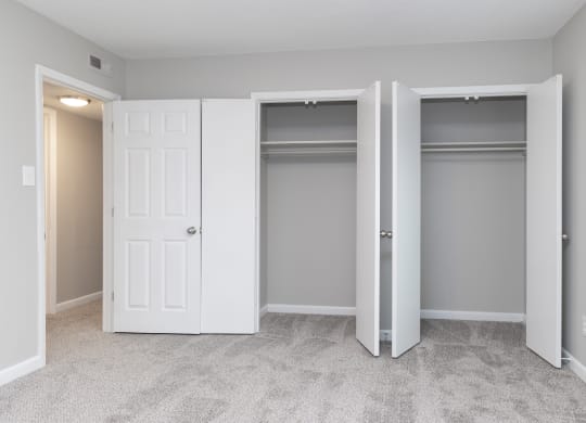 an empty bedroom with two closets and two doors