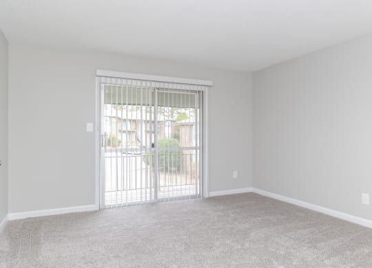 an empty living room with a sliding glass door to a patio