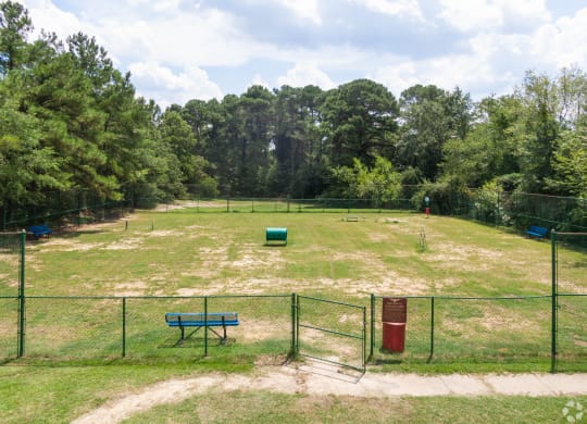 a pet park with a fenced in field and a park bench