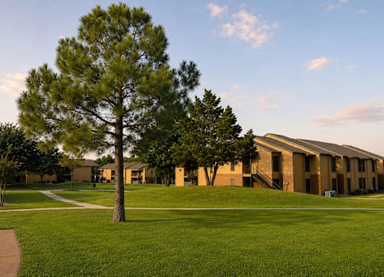 Exterior buildings with lawn and mature trees at Ridgeview Apartments, Texas, 75092