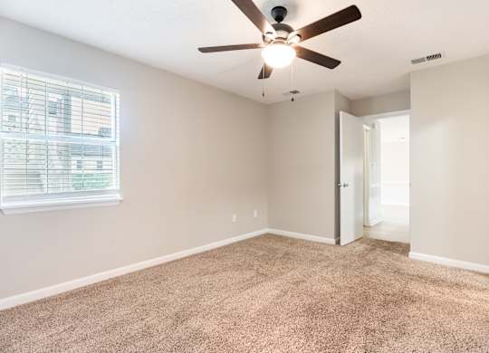 A room with a ceiling fan and carpeted floor. at Rosewood at Colony Square, Rocky Mount, NC
