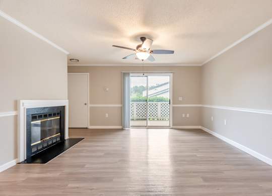 A spacious living room with a fireplace and sliding glass doors leading to a balcony. at Rosewood at Colony Square, Rocky Mount, NC