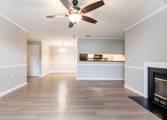 A living room with a fireplace and a ceiling fan. at Rosewood at Colony Square, Rocky Mount, 27804