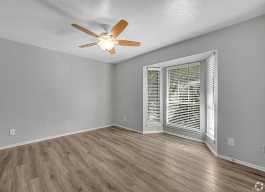 A room with a ceiling fan and wooden flooring.