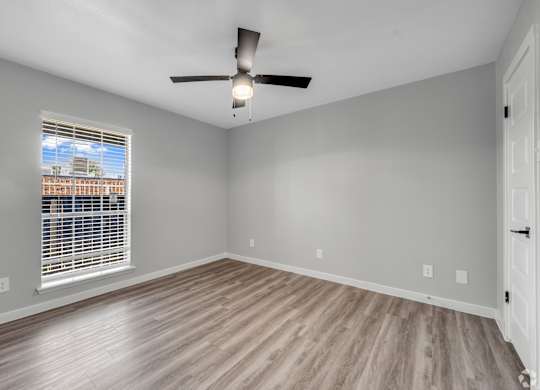 A room with a ceiling fan and a window with blinds.