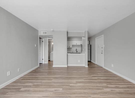 A spacious room with wooden flooring and white walls.