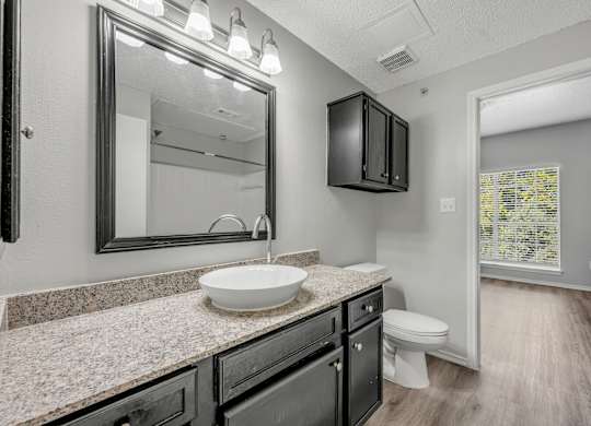 A bathroom with a sink, mirror, and toilet.