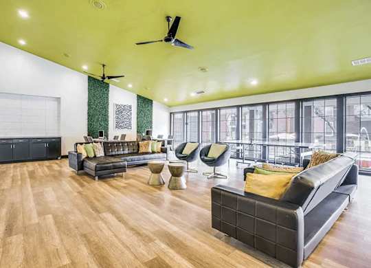 A spacious living room with a black sofa and wooden flooring.