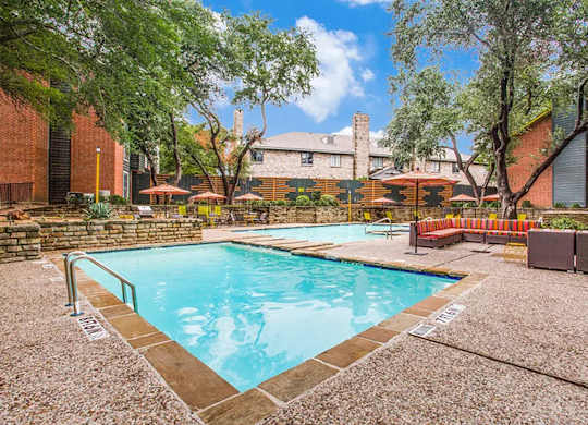 A pool surrounded by trees and a building in the background.