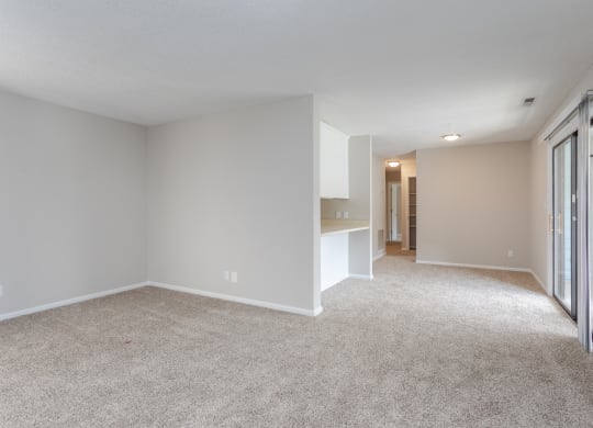 a spacious living room with white carpet and a door to a hallway