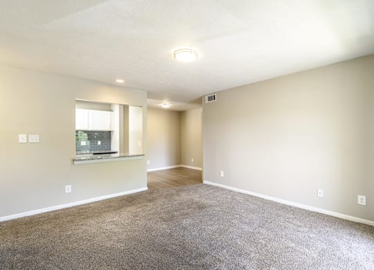 A spacious room with a window and carpeted floor.