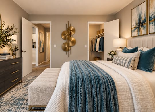 A bedroom with a large bed and a dresser with a plant on top.