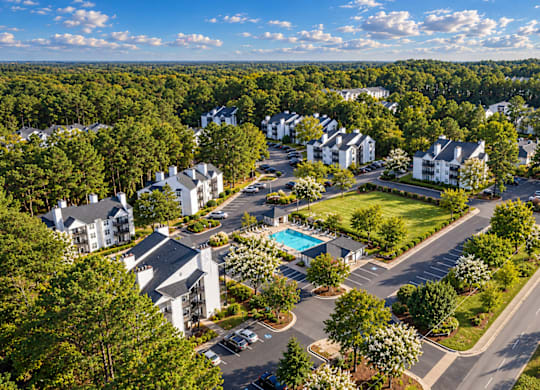 A bird's eye view of a residential area with houses, roads, and a swimming pool.