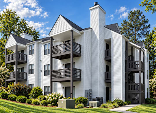 A white apartment building with black balconies and a black gate.