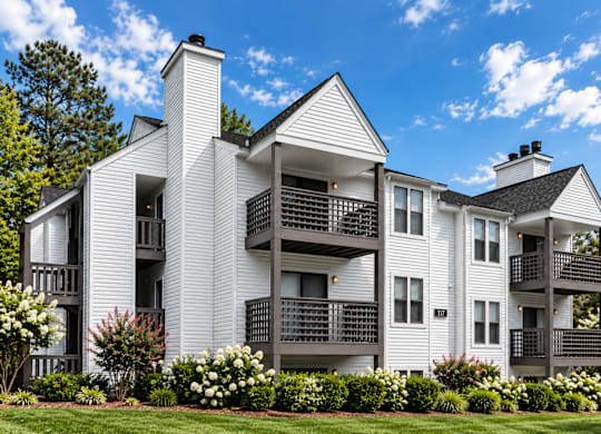 A white two story house with a balcony on the second floor.