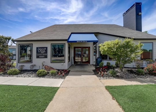 the front of a white building with a sidewalk and lawn