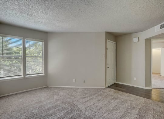 an empty living room with large windows and a door