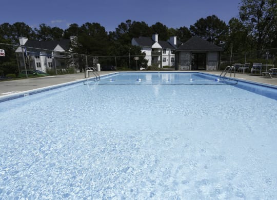 a large swimming pool with chairs and a fence around it