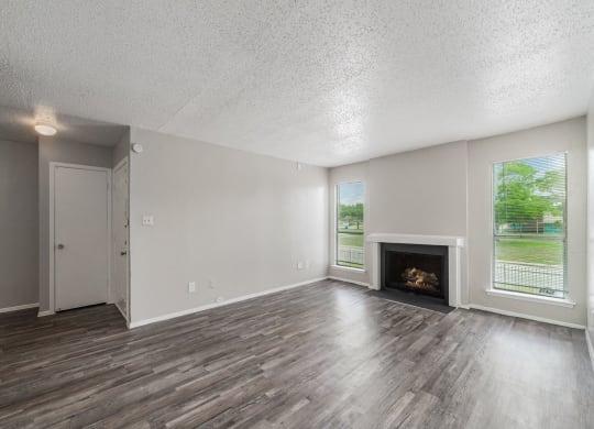an empty living room with a fireplace and a window at Helios, Dallas, TX