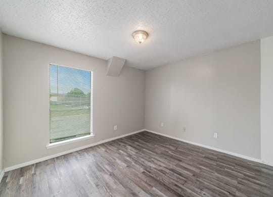 an empty living room with wood flooring and a large window at Helios, Dallas, 75240