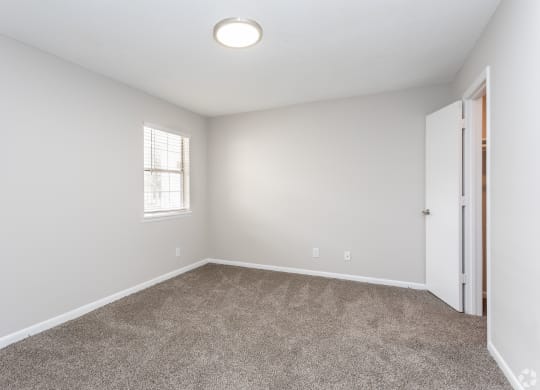 an empty bedroom with carpet and a door to a closet