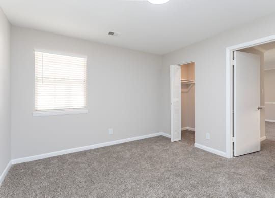 an empty bedroom with a closet and an open door