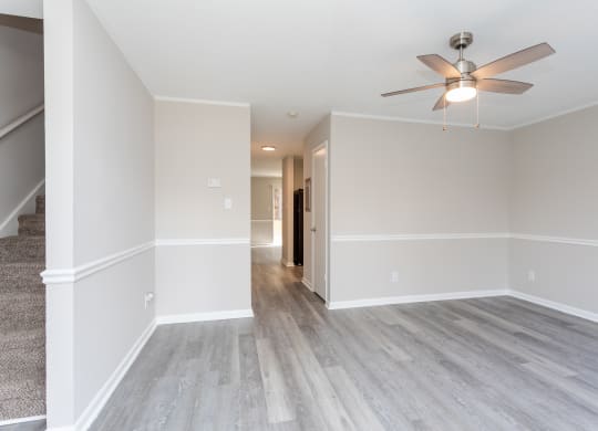 an empty living room with white walls and a ceiling fan