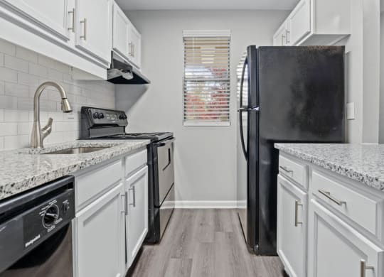 a kitchen with white cabinets and a black refrigerator