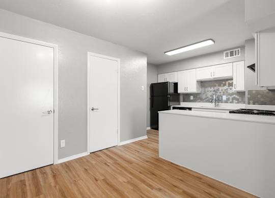 A kitchen with white cabinets and a black fridge.at The Sidney, Sherman Texas