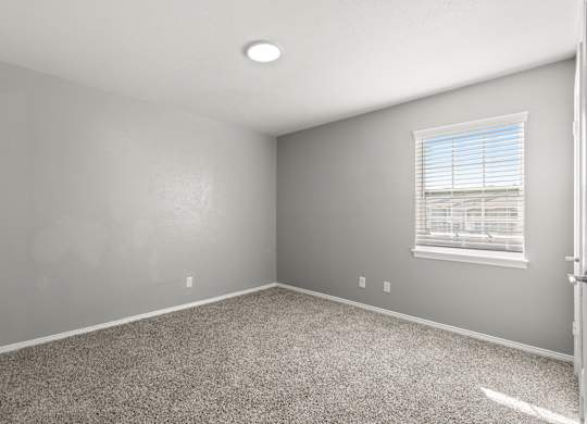 A room with a carpeted floor and a window with blinds.at The Sidney, Sherman Texas