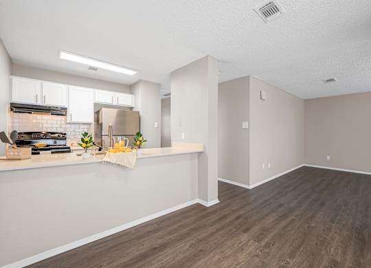 an empty living room and kitchen with a wood floor