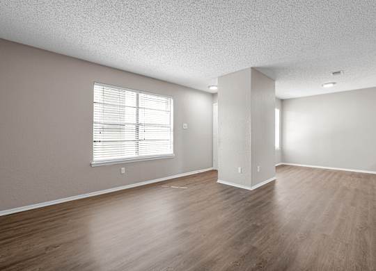 an empty living room with wood floors and a window