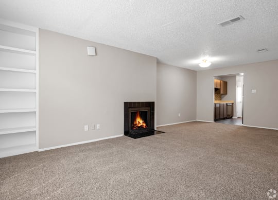 an empty living room with a fireplace and white shelves