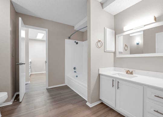 a bathroom with white cabinets and a shower and a sink