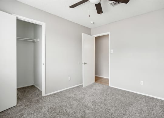an empty bedroom with a closet and a ceiling fan