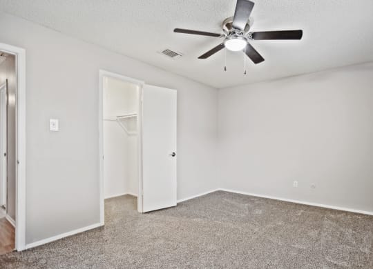 an empty room with a ceiling fan and a closet