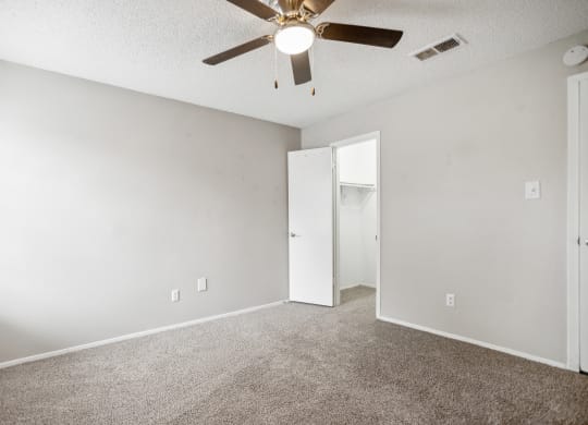 an empty living room with a ceiling fan and a closet