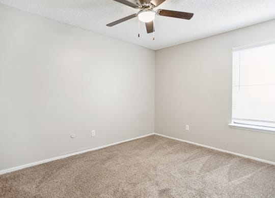 an empty room with a ceiling fan and a window