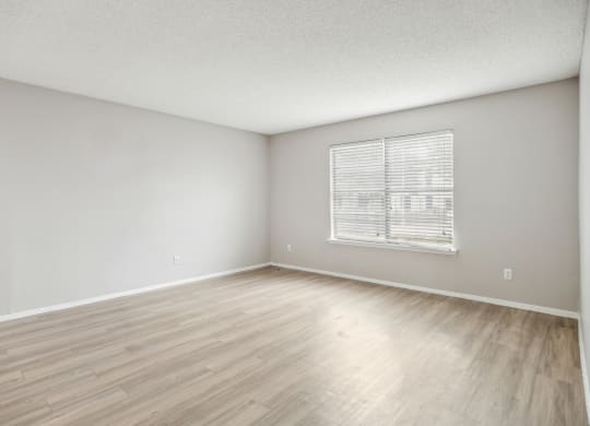 the spacious living room with wood flooring and a window