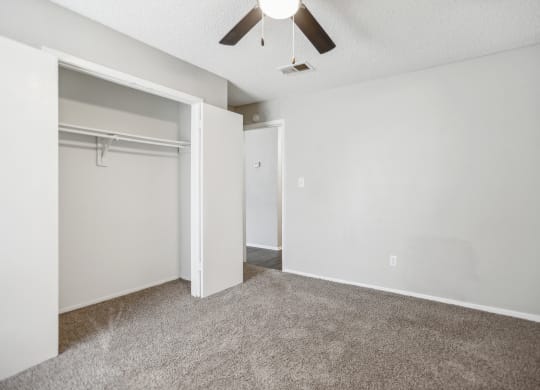 an empty living room with a closet and a ceiling fan
