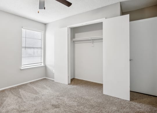 an empty bedroom with a closet and a window