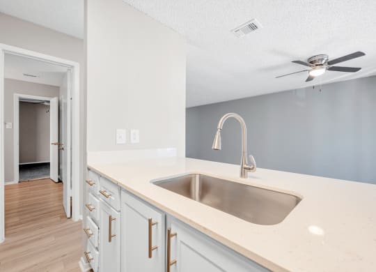 an empty kitchen with a sink and a ceiling fan