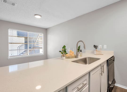 a white kitchen with a sink and a window