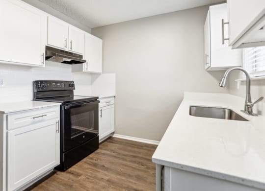 an empty kitchen with white cabinets and a black stove and sink