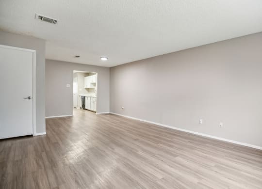 the living room and dining room of an apartment with wood flooring