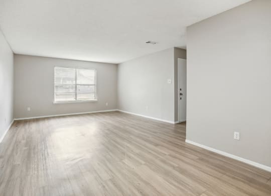 an empty living room with hardwood floors and a window