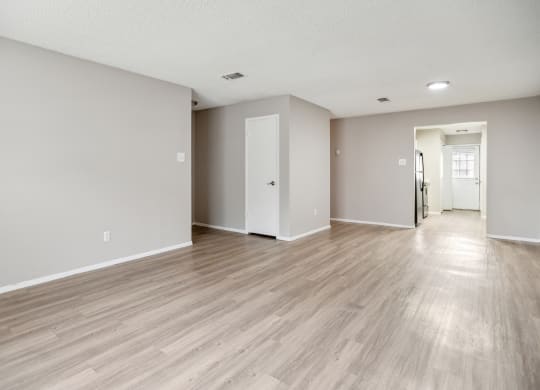 the living room and dining room of an apartment with wood floors and white walls