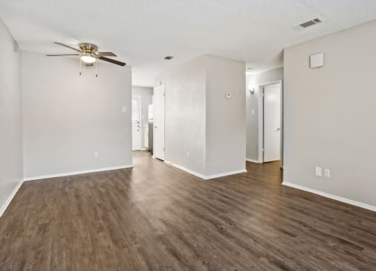 an empty living room with white walls and a ceiling fan
