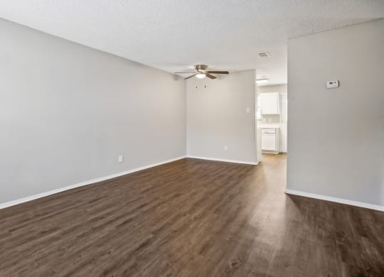 an empty living room with wood flooring and a ceiling fan
